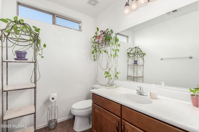 half bath with toilet, a wealth of natural light, vanity, and visible vents
