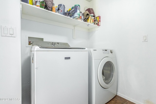 clothes washing area with baseboards, washing machine and dryer, and laundry area