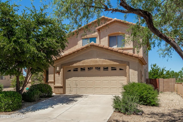 mediterranean / spanish-style home featuring a tile roof, concrete driveway, stucco siding, fence, and a garage