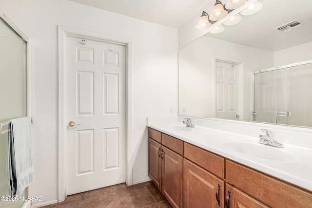 full bathroom featuring double vanity, a sink, a shower with door, and visible vents