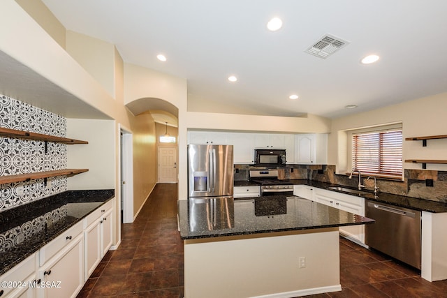 kitchen with stainless steel appliances, vaulted ceiling, sink, white cabinets, and a kitchen island