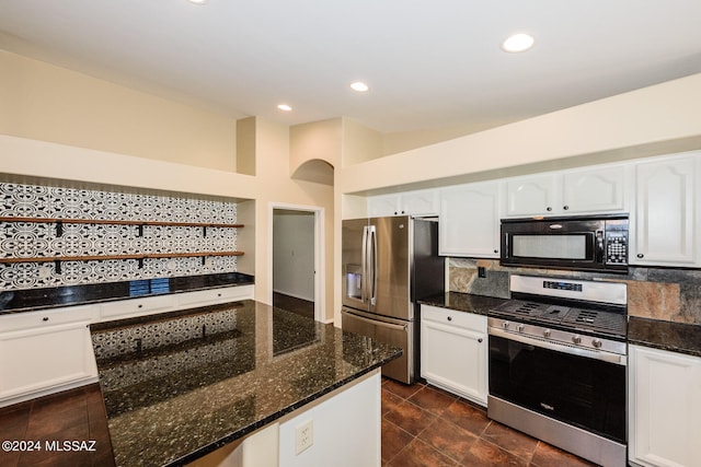 kitchen featuring white cabinets, backsplash, stainless steel appliances, and dark stone counters