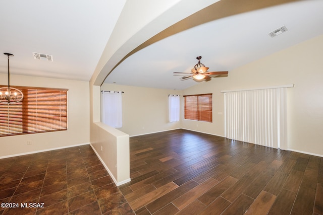 empty room featuring ceiling fan with notable chandelier, dark hardwood / wood-style flooring, plenty of natural light, and lofted ceiling