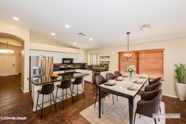 dining area featuring a notable chandelier, lofted ceiling, and sink