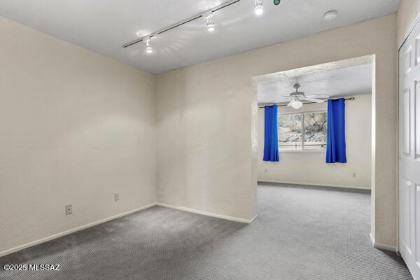 unfurnished room featuring ceiling fan, rail lighting, and carpet floors