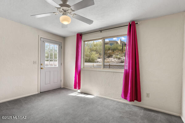 unfurnished room featuring carpet floors, a textured ceiling, a wealth of natural light, and ceiling fan