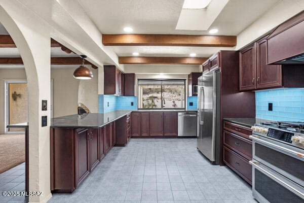 kitchen with sink, appliances with stainless steel finishes, hanging light fixtures, backsplash, and beamed ceiling