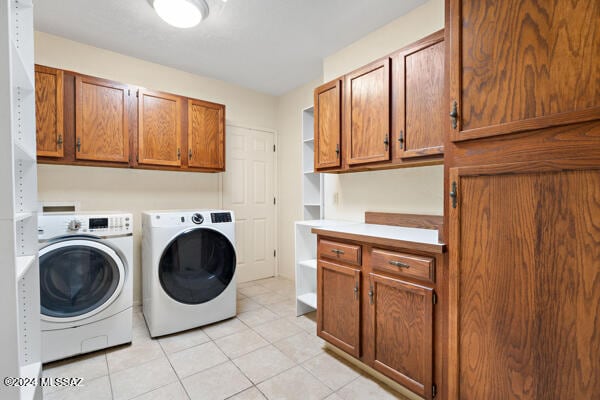 laundry area with cabinets, washer and dryer, and light tile patterned floors