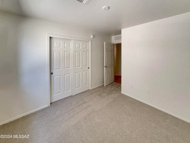 unfurnished bedroom with a closet and light carpet