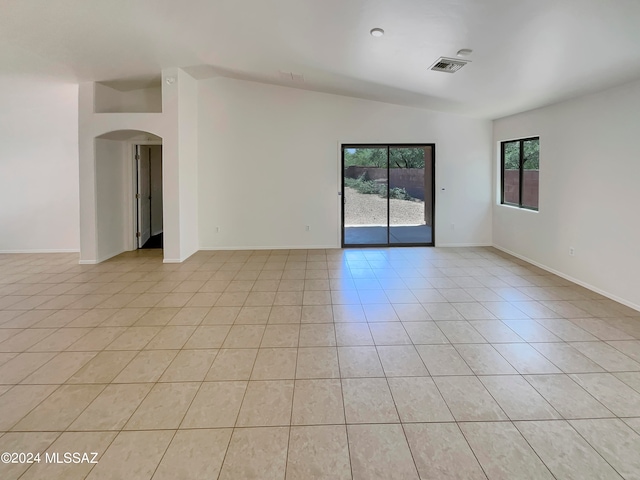 empty room featuring vaulted ceiling and light tile patterned floors