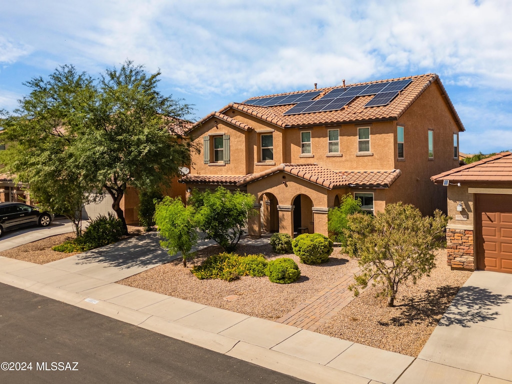 mediterranean / spanish home with concrete driveway, stone siding, a tiled roof, roof mounted solar panels, and stucco siding