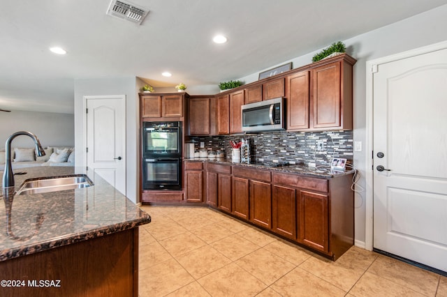 kitchen with dark stone counters, tasteful backsplash, light tile patterned floors, sink, and black appliances