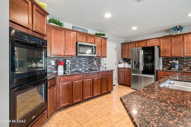 kitchen featuring light tile patterned flooring, tasteful backsplash, dark stone countertops, and black appliances