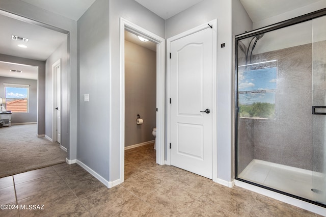 bathroom with toilet, tile patterned flooring, and a shower with shower door