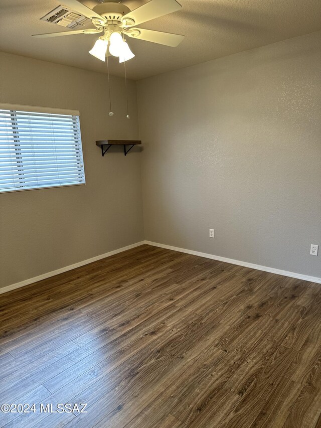 empty room with ceiling fan and dark wood-type flooring