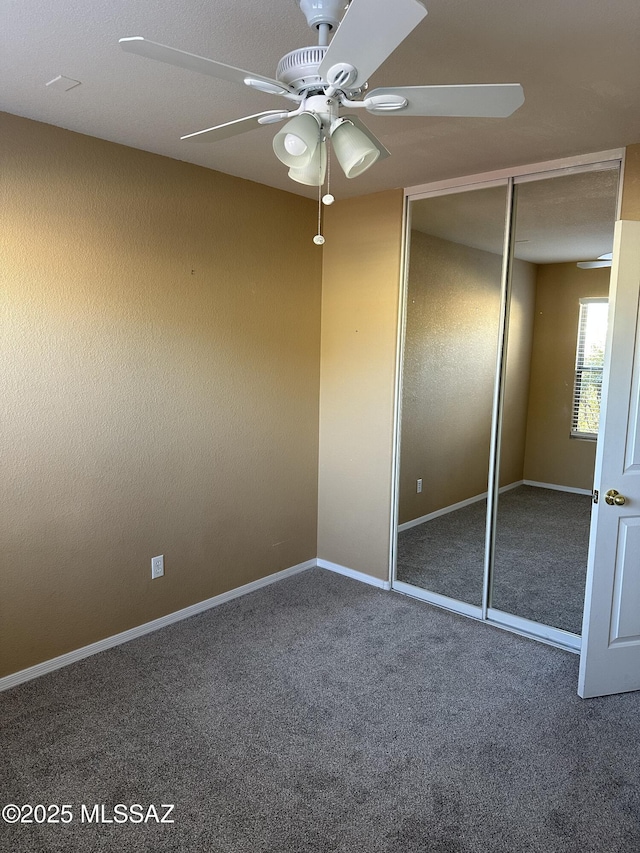 unfurnished bedroom with ceiling fan, a closet, and dark colored carpet