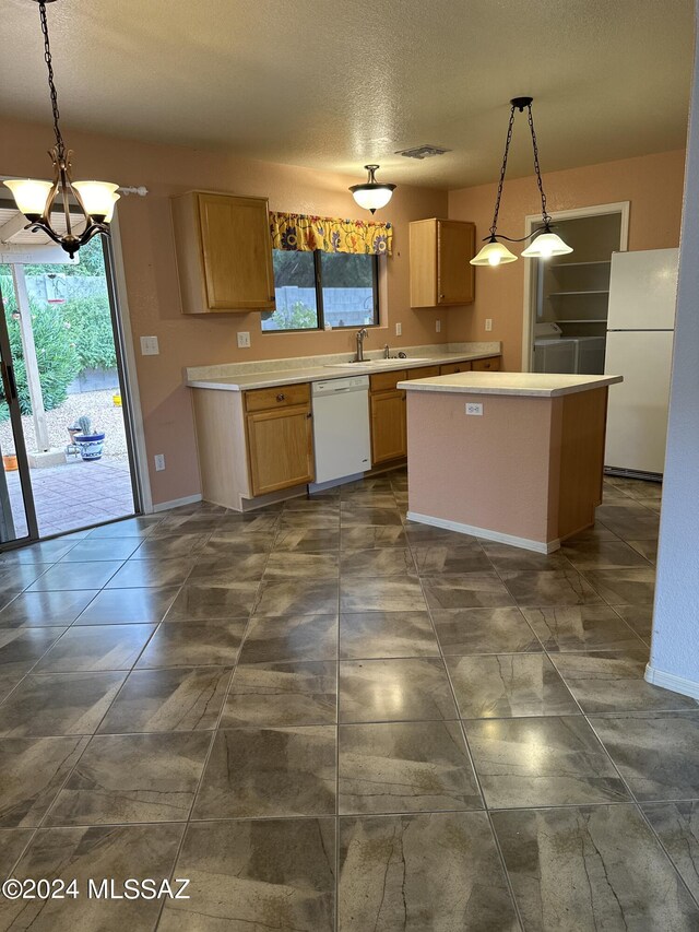 kitchen featuring pendant lighting, a center island, white appliances, a textured ceiling, and a chandelier