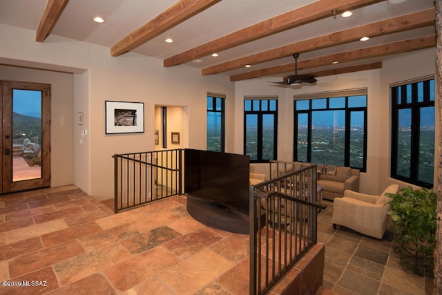 living room with a mountain view, ceiling fan, and beamed ceiling