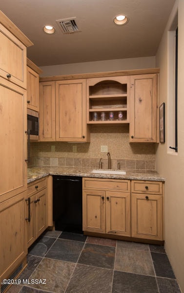 kitchen featuring light stone counters, sink, tasteful backsplash, dishwasher, and light brown cabinetry