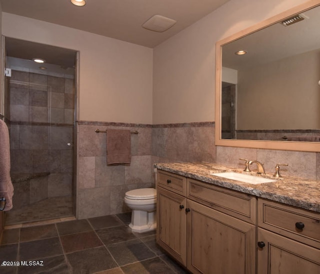 bathroom featuring tile walls, vanity, toilet, and an enclosed shower