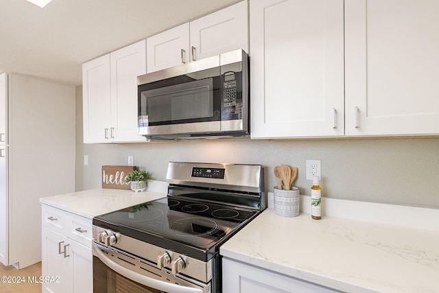 kitchen featuring stainless steel appliances, white cabinetry, and light stone countertops