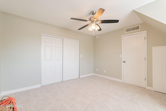 unfurnished bedroom featuring carpet floors, ceiling fan, vaulted ceiling, and a closet