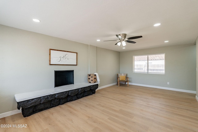 unfurnished living room featuring ceiling fan, a fireplace, and light hardwood / wood-style flooring