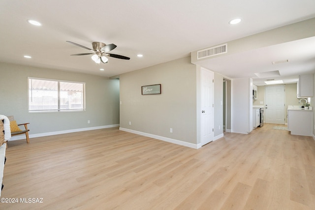 unfurnished living room featuring sink, light hardwood / wood-style flooring, and ceiling fan