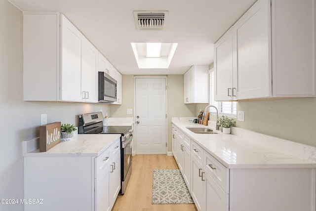 kitchen with light hardwood / wood-style flooring, white cabinetry, appliances with stainless steel finishes, light stone counters, and sink