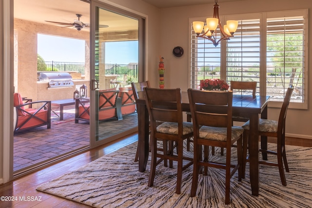 dining room with ceiling fan with notable chandelier and wood-type flooring