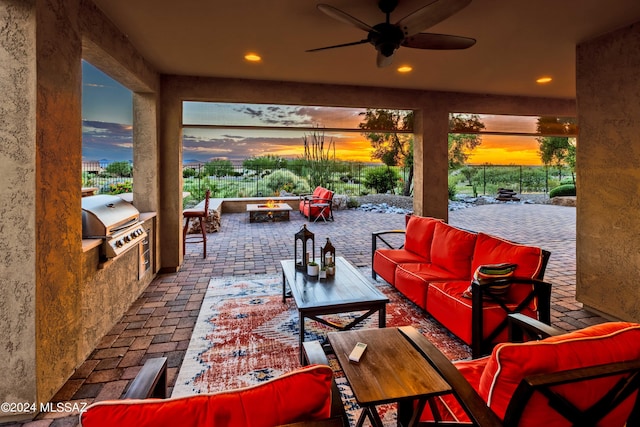 patio terrace at dusk featuring area for grilling, an outdoor living space with a fire pit, and ceiling fan