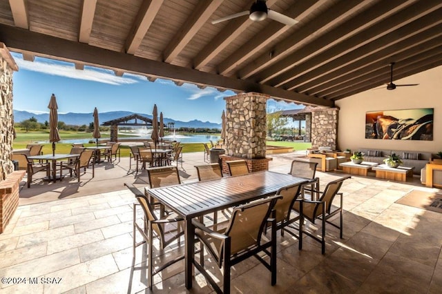 view of patio featuring ceiling fan, a water and mountain view, and an outdoor stone fireplace