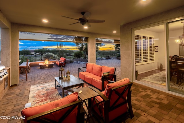 patio terrace at dusk with ceiling fan and an outdoor living space with a fire pit