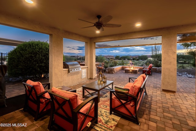 patio terrace at dusk with grilling area, an outdoor kitchen, an outdoor living space with a fire pit, and ceiling fan