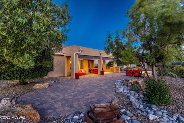 rear view of property featuring outdoor lounge area, a patio, and an outdoor kitchen