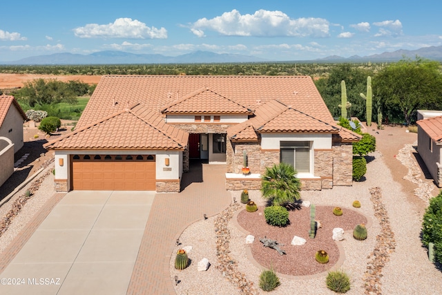 mediterranean / spanish home featuring a mountain view, stone siding, a tiled roof, and stucco siding