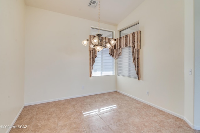 empty room featuring a chandelier, lofted ceiling, visible vents, and baseboards