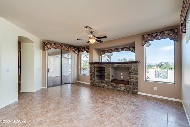 unfurnished living room with ceiling fan, arched walkways, visible vents, and baseboards