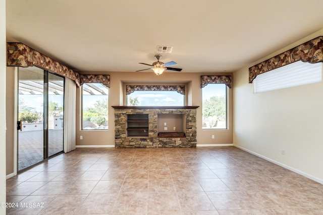 unfurnished living room featuring ceiling fan, a wealth of natural light, visible vents, and baseboards