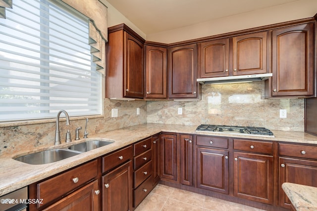 kitchen with light stone countertops, stainless steel gas cooktop, decorative backsplash, and a sink