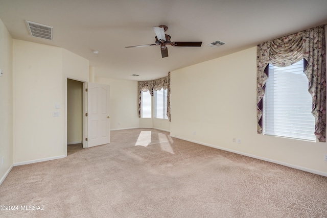 spare room with light colored carpet, visible vents, and baseboards