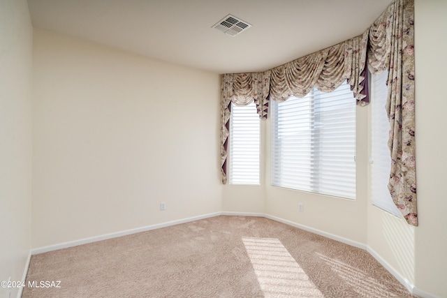 empty room with carpet, visible vents, and baseboards