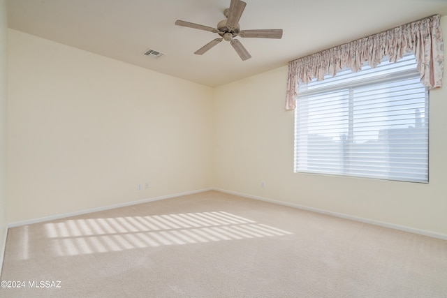 carpeted empty room featuring baseboards, visible vents, and ceiling fan