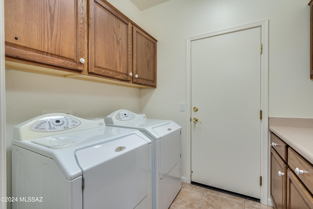 clothes washing area featuring washer and dryer, cabinet space, and light tile patterned flooring