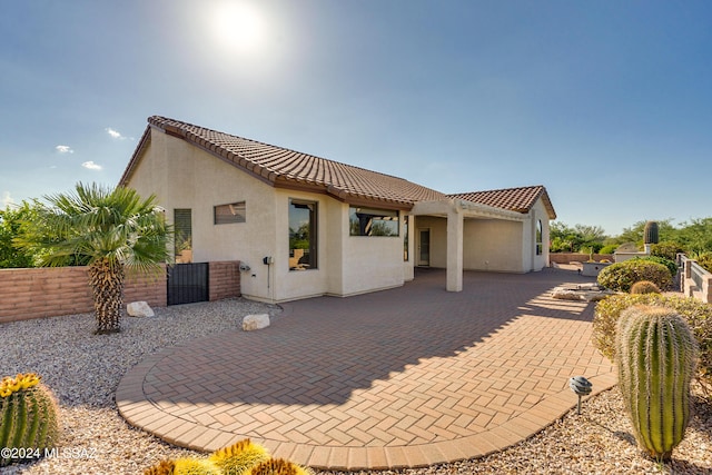 back of house featuring a patio area, a tiled roof, fence, and stucco siding