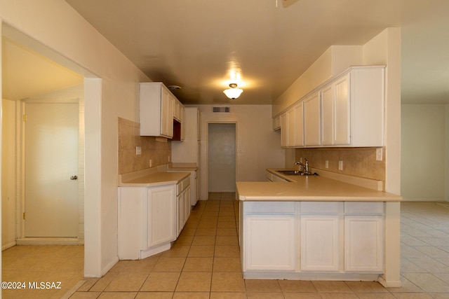 kitchen with white cabinetry, sink, decorative backsplash, and light tile patterned flooring