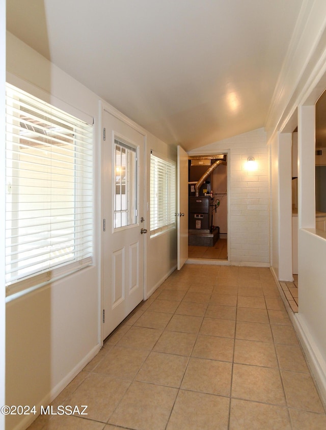 doorway featuring light tile patterned flooring and vaulted ceiling