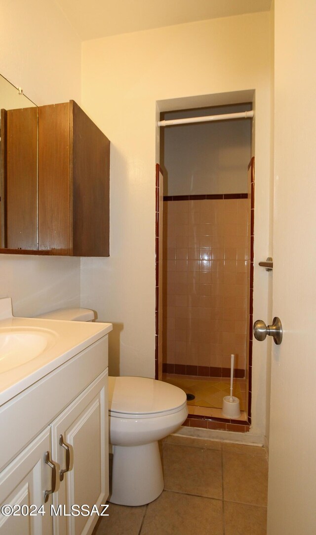 bathroom with tile patterned flooring, vanity, a tile shower, and toilet