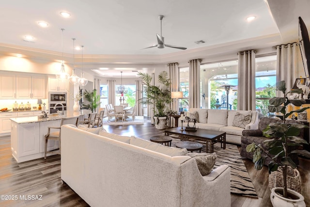 living room featuring ceiling fan, dark hardwood / wood-style floors, crown molding, and a tray ceiling