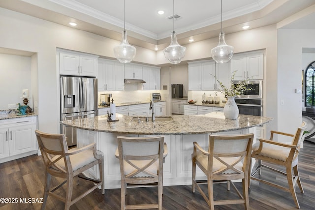 kitchen with white cabinets, stainless steel fridge, sink, and hanging light fixtures